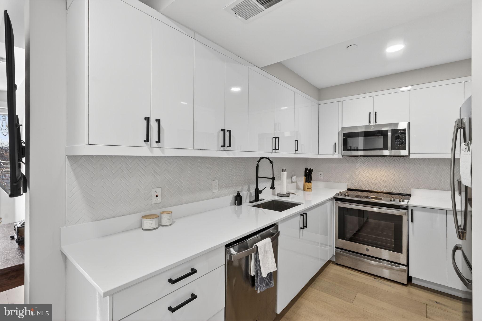 919 12th Street Northeast, Unit 305 Washington, DC 20002 - Photo 9 of 31 a kitchen with stainless steel appliances granite countertop a sink stove oven and white cabinets