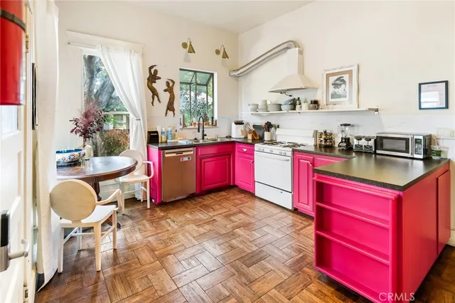 a kitchen with stainless steel appliances granite countertop a stove a sink dishwasher a dining table and chairs with wooden floor