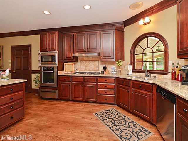 8231 Stafford Mill Road Oak Ridge, NC 27310 - Photo 7 of 16 Kitchen. Another view of the work are in the kitchen including built in oven and microwave, warming drawer, dishwasher and view of the private rear yard through the arched window. No tripping over anyone in this kitchen with LOTS of room!