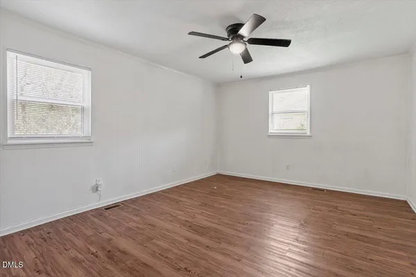 a view of a big room with wooden floor and windows