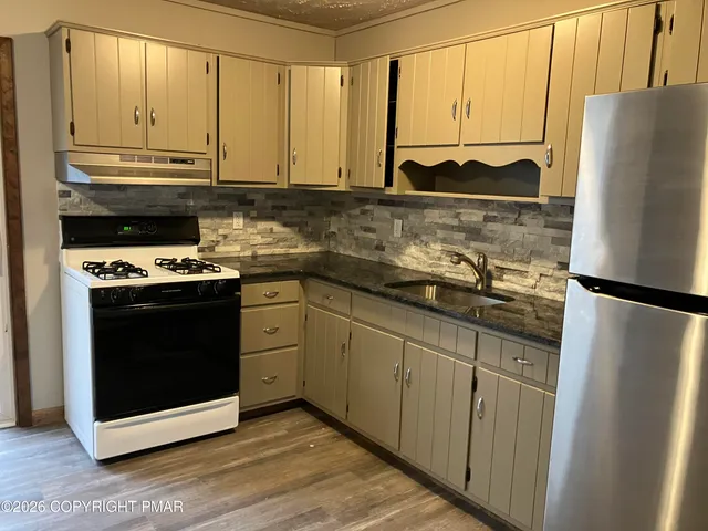 a kitchen with stainless steel appliances a stove a refrigerator and a sink