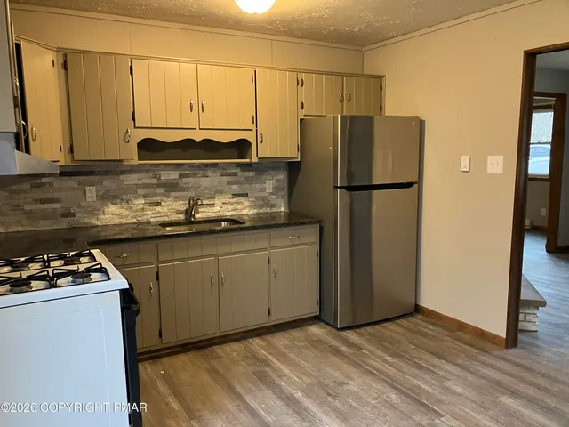 a kitchen with a refrigerator a stove a sink and cabinets