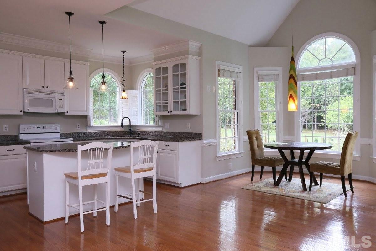 2621 Lizei Street Raleigh, NC 27616 - Photo 7 of 25 a kitchen with a dining table chairs and white cabinets