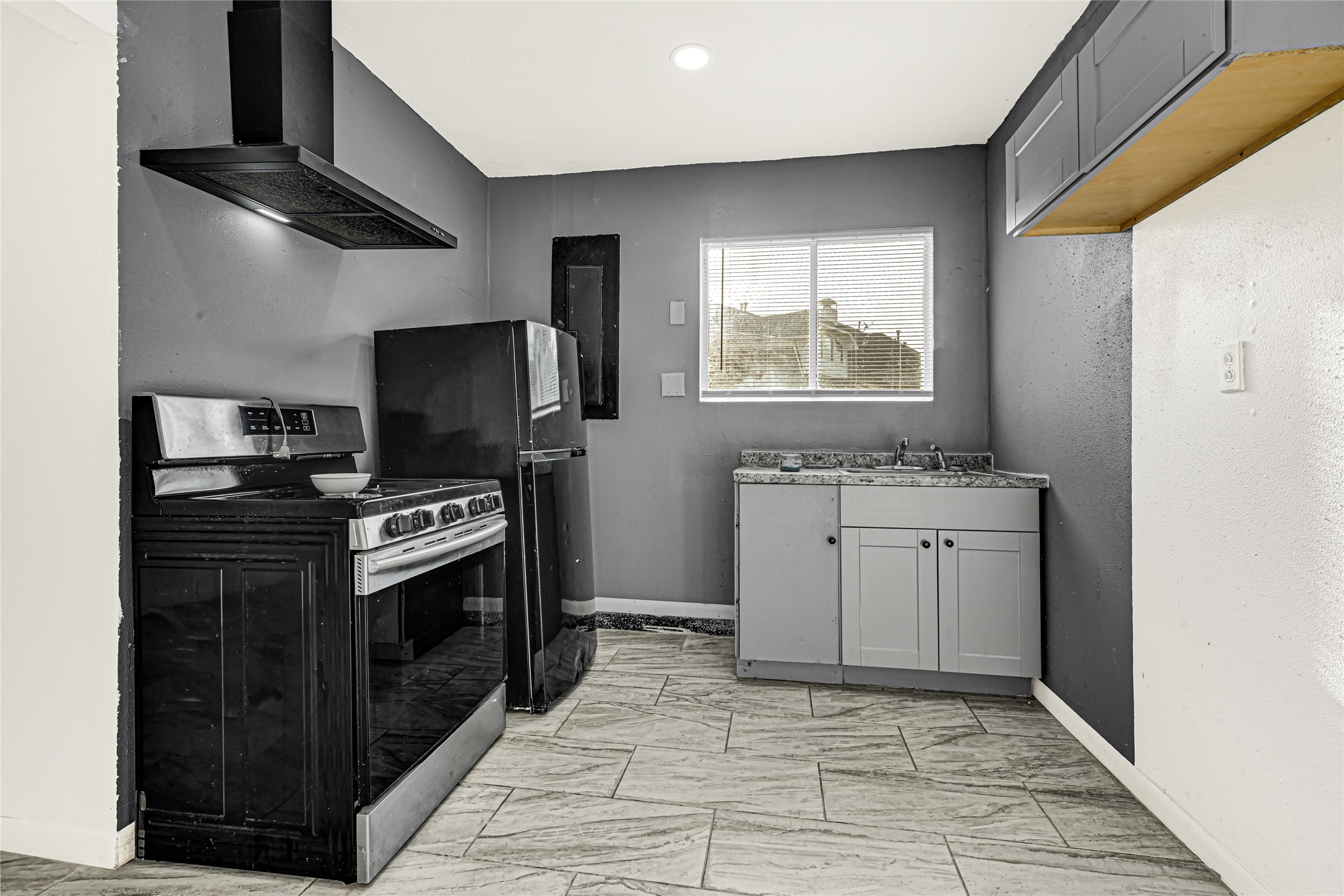 14714 Placid Point Humble, TX 77396 - Photo 6 of 37 This features the mother-in-Law suite with a Compact kitchen with appliances. The space includes a small sink with gray cabinetry, tiled flooring, and a window for natural light.