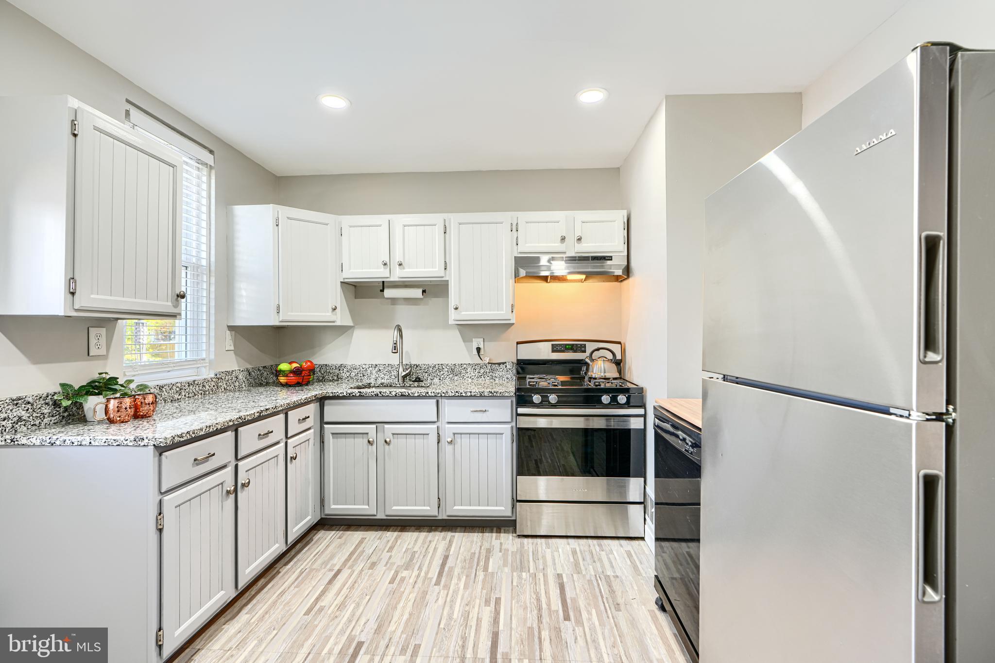 1620 Naturo Road Towson, MD 21286 - Photo 4 of 43 a kitchen with a refrigerator a sink dishwasher a stove and white cabinets with wooden floor