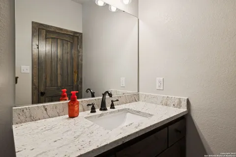 a bathroom with a granite countertop sink and a mirror