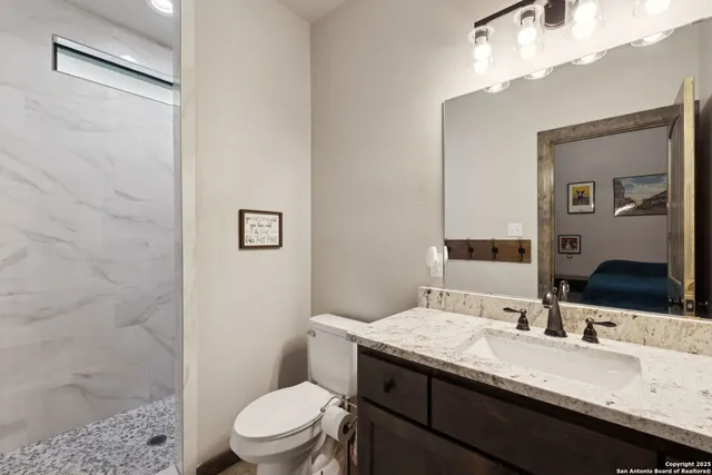 a bathroom with a granite countertop toilet sink and mirror