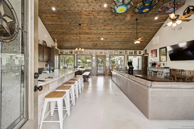 a kitchen with stainless steel appliances kitchen island granite countertop a refrigerator a stove a dining table and chairs with wooden floor