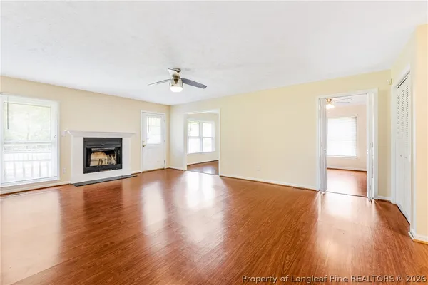 a view of an empty room with window and wooden floor