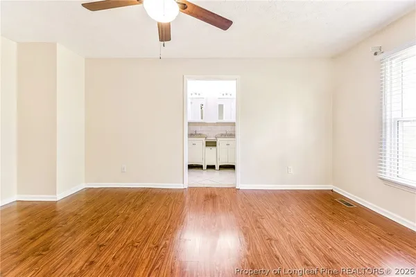 a view of a room with wooden floor ceiling fan and windows