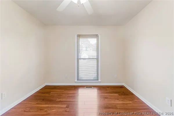 a view of empty room with wooden floor and fan