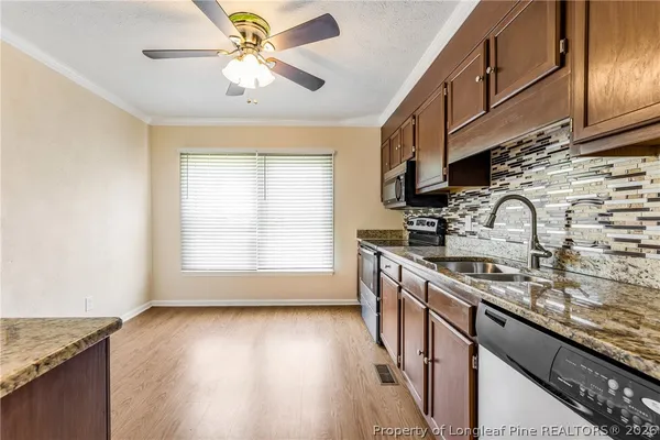 a kitchen with stainless steel appliances granite countertop a sink a stove cabinets and wooden floor