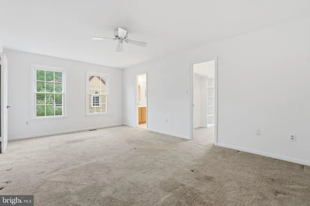 an empty room with windows and ceiling fan