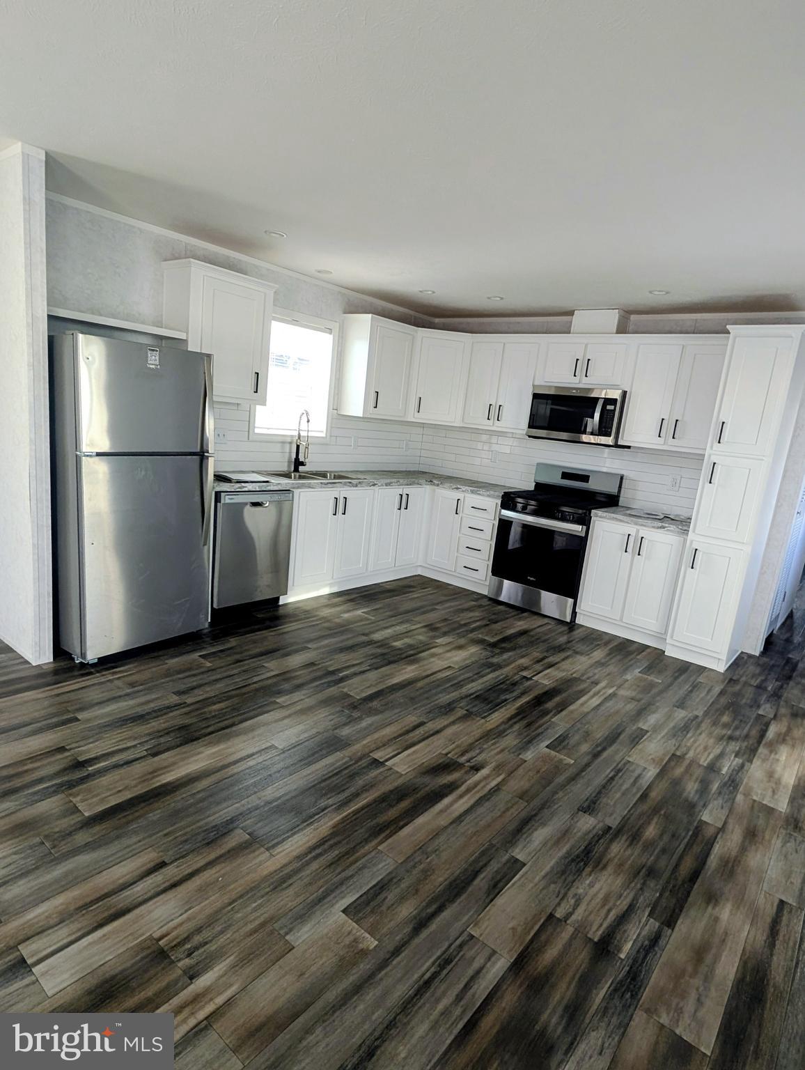 16 Abbey Road Coatesville, PA 19320 - Photo 4 of 8 a kitchen with stainless steel appliances wooden floor and a refrigerator