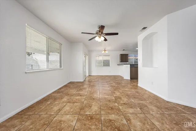 a view of an empty room with a ceiling fan and windows