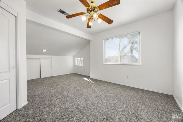 an empty room with windows and fan