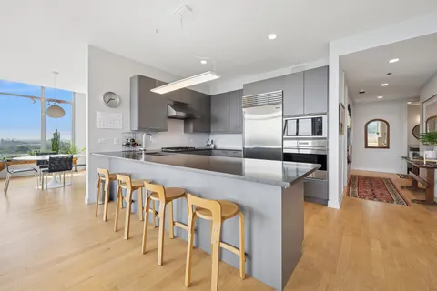 a kitchen with stainless steel appliances granite countertop a stove a sink a refrigerator and chairs