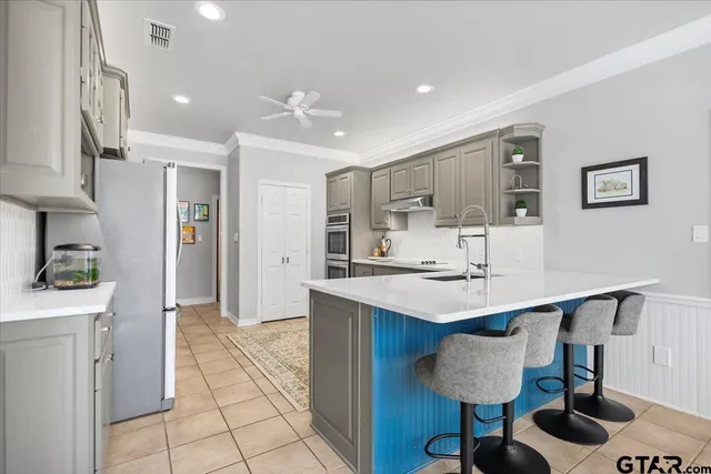a kitchen with stainless steel appliances kitchen island a table chairs in it and wooden floors
