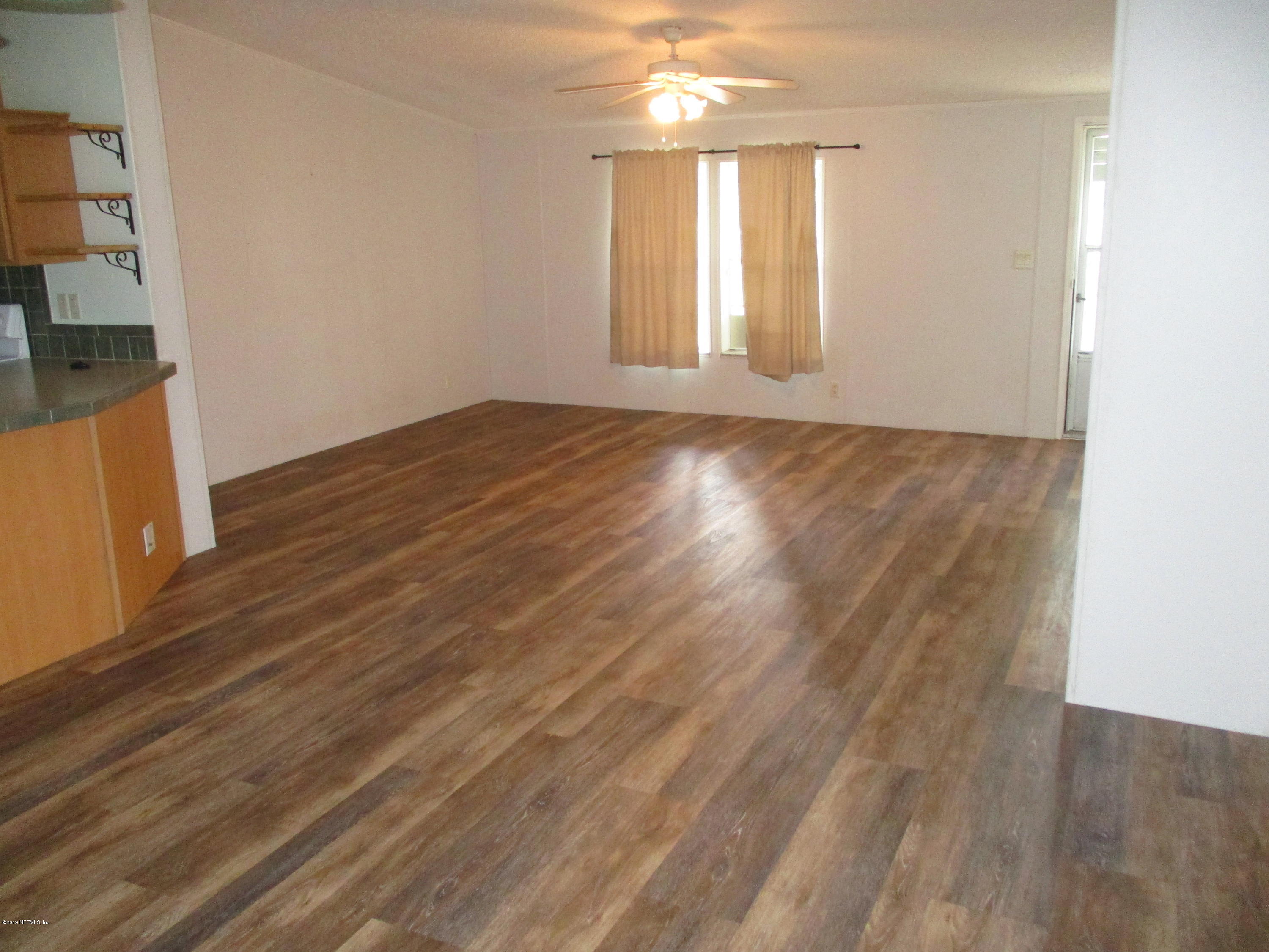 45549 Zidell Road Callahan, FL 32011 - Photo 15 of 41 an empty room with wooden floor and windows with curtains