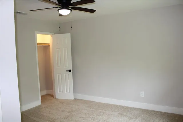 an empty room with closet and a chandelier fan
