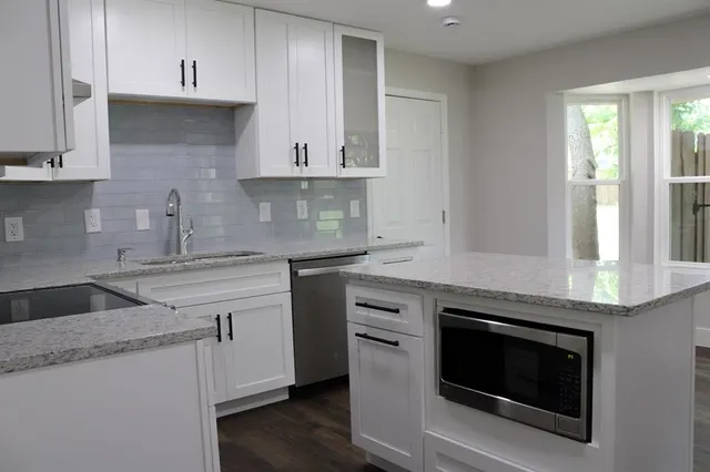 a kitchen with granite countertop white cabinets and a stove