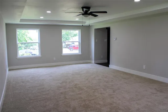 an empty room with windows and fan