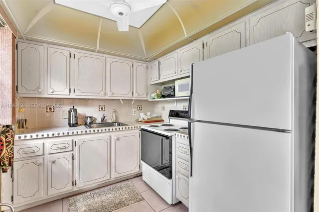 a kitchen with stainless steel appliances granite countertop a refrigerator sink stove and white cabinets