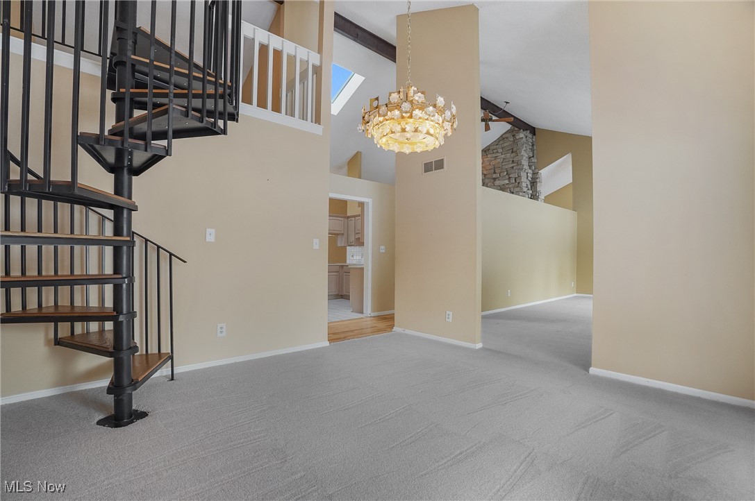 1094 San Raphael Drive Akron, OH 44333 - Photo 25 of 50 Unfurnished living room featuring carpet flooring, a chandelier, high vaulted ceiling, stairway, and beam ceiling