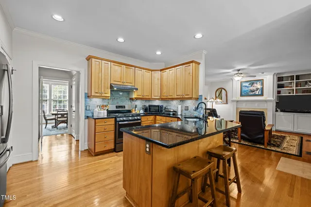 a kitchen with granite countertop a stove a sink a dining table and chairs