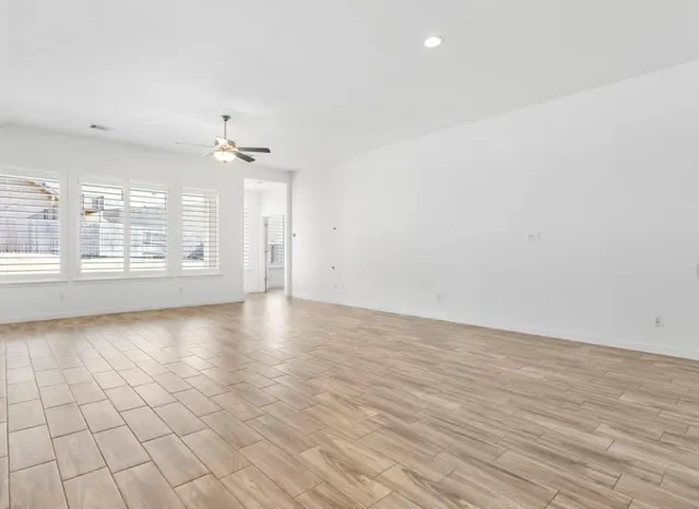 an empty room with wooden floor and windows