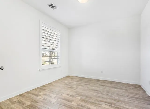an empty room with wooden floor and windows