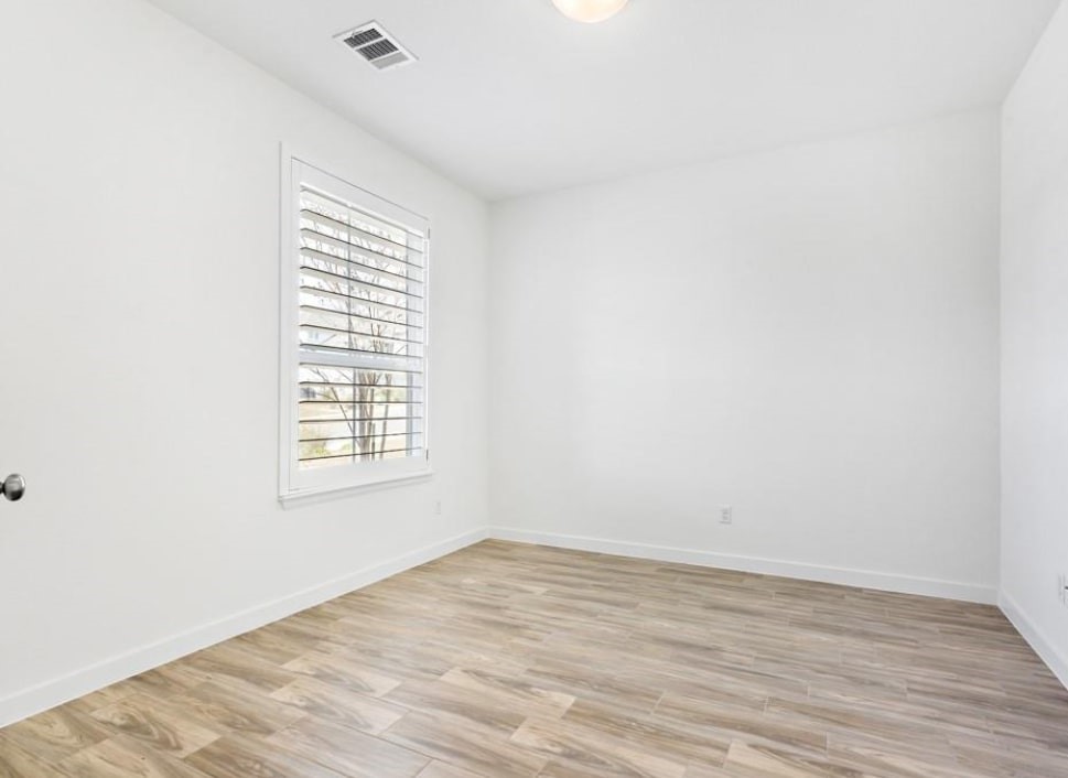 121 San Domenico Cove Georgetown, TX 78628 - Photo 4 of 24 an empty room with wooden floor and windows