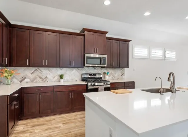 a kitchen with stainless steel appliances granite countertop a sink stove and microwave