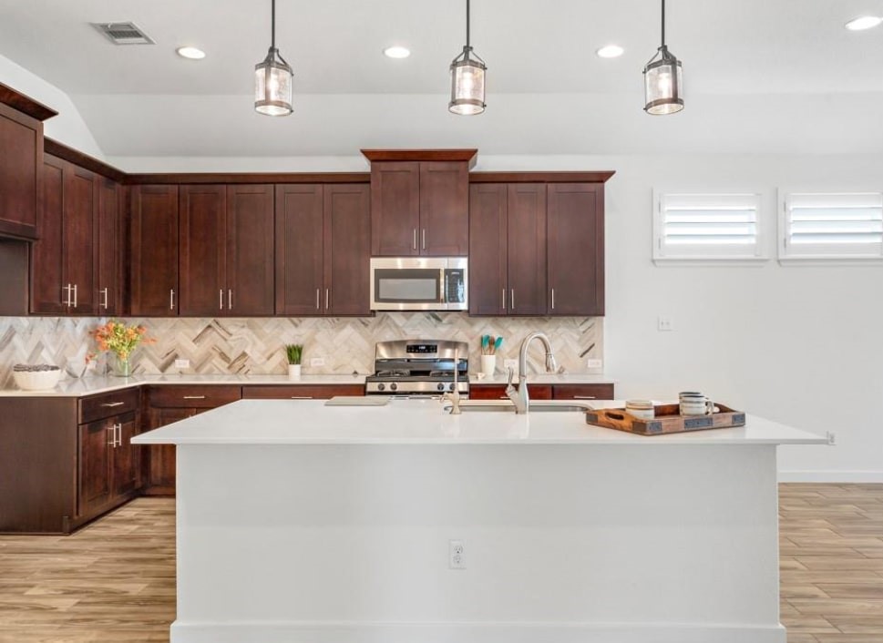 121 San Domenico Cove Georgetown, TX 78628 - Photo 8 of 24 a kitchen with stainless steel appliances granite countertop wooden cabinets a sink a stove a refrigerator and island with wooden floor