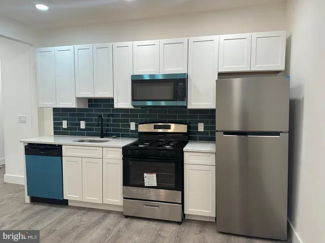 a kitchen with a refrigerator stove and white cabinets