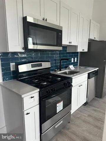 a kitchen with granite countertop white cabinets and black appliances