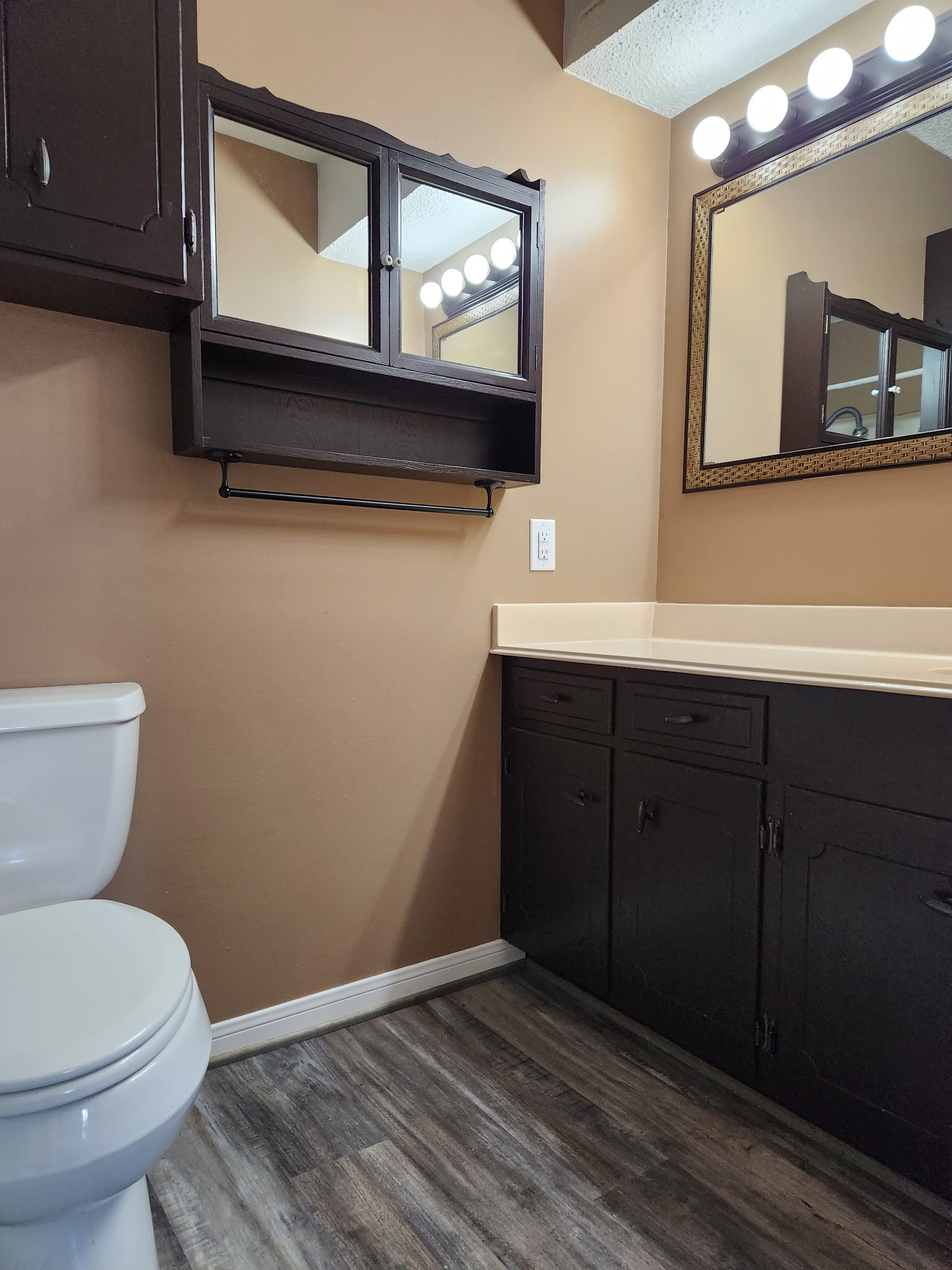 1252 Eagle Lake Road, Unit 8 Sealy, TX 77474 - Photo 13 of 18 This bathroom features a classic design with a white bathtub and tiled shower area. It includes a sink with a countertop, and dark wood cabinetry for storage. The flooring is a wood-like laminate, adding a modern touch.