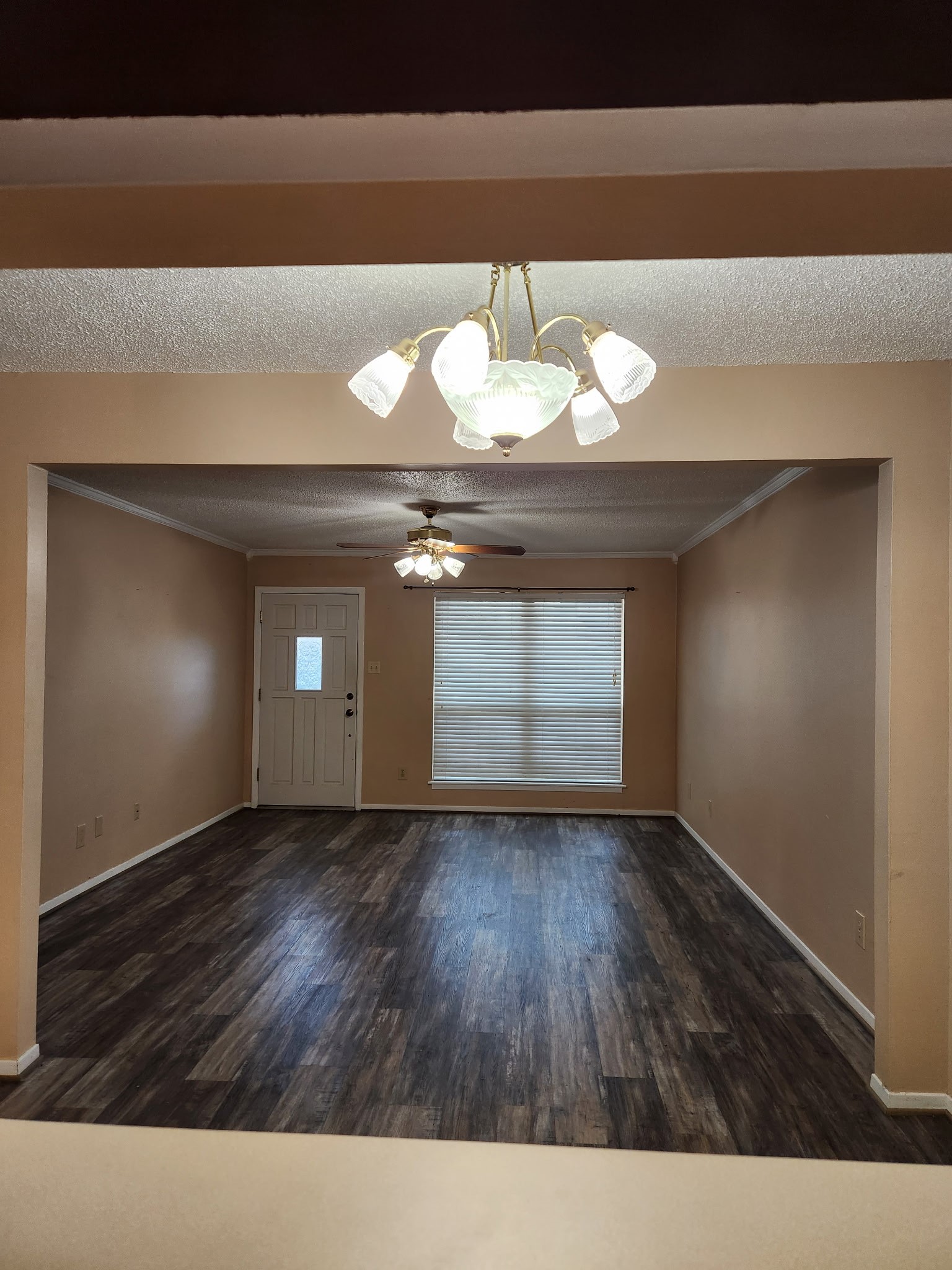 1252 Eagle Lake Road, Unit 8 Sealy, TX 77474 - Photo 2 of 18 a spacious living area with dark wood flooring, neutral walls, a ceiling fan, and a large window for natural light. The room is open and inviting, perfect for entertaining or relaxing.