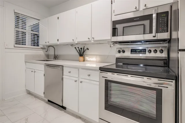 a kitchen with white cabinets and white appliances