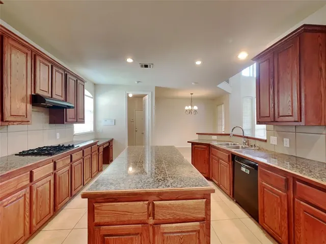 a kitchen with kitchen island granite countertop wooden cabinets and a refrigerator