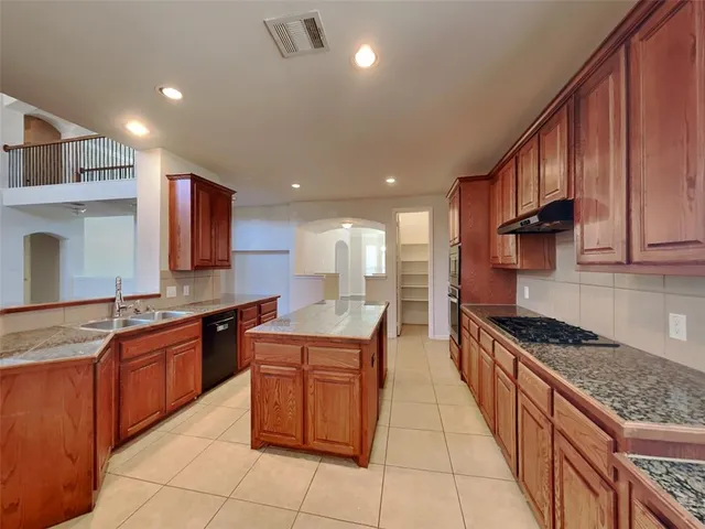 a kitchen with stainless steel appliances granite countertop wooden cabinets a stove top oven a sink and dishwasher