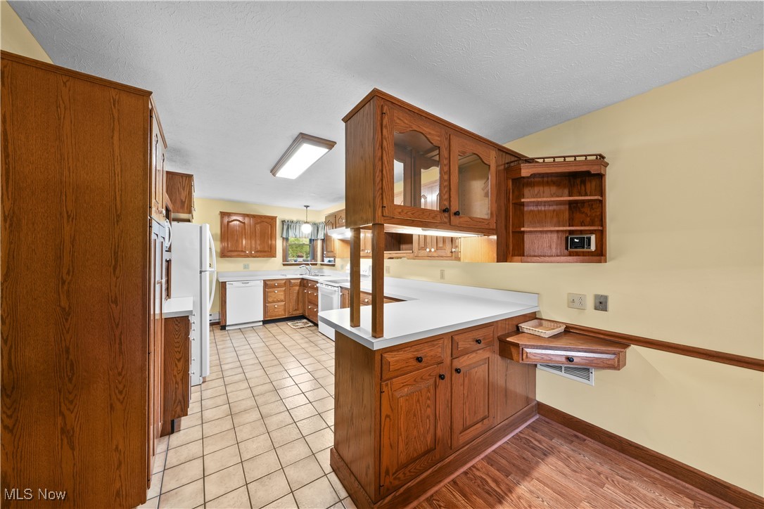 10 Kehner Road Mogadore, OH 44260 - Photo 6 of 32 Kitchen with a textured ceiling, kitchen peninsula, light wood-type flooring, and white dishwasher