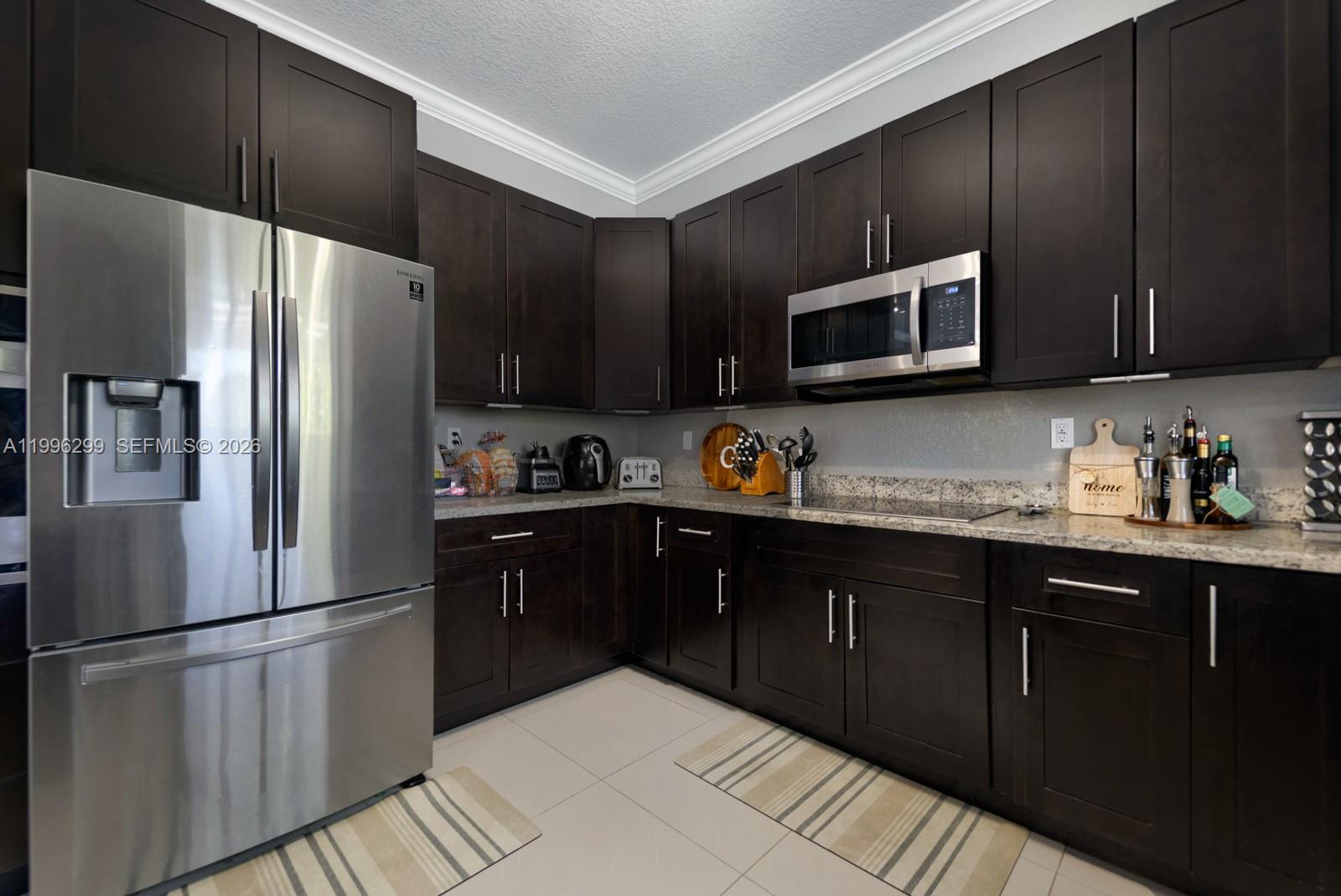 19781 Southwest 84th Court Cutler Bay, FL 33189 - Photo 12 of 53 a kitchen with granite countertop stainless steel appliances a refrigerator sink and microwave