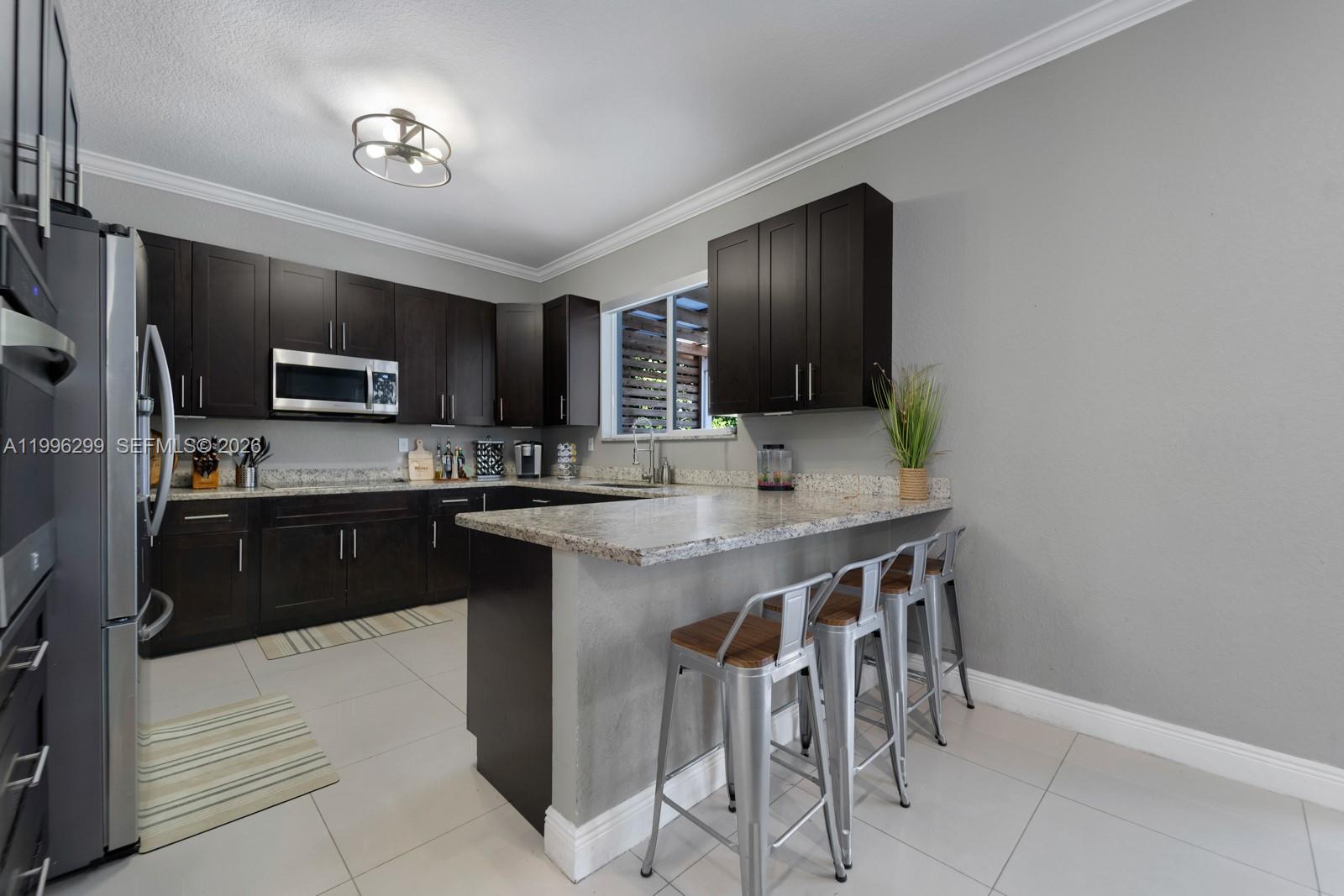 19781 Southwest 84th Court Cutler Bay, FL 33189 - Photo 14 of 53 a kitchen with stainless steel appliances kitchen island granite countertop a stove a sink and a refrigerator