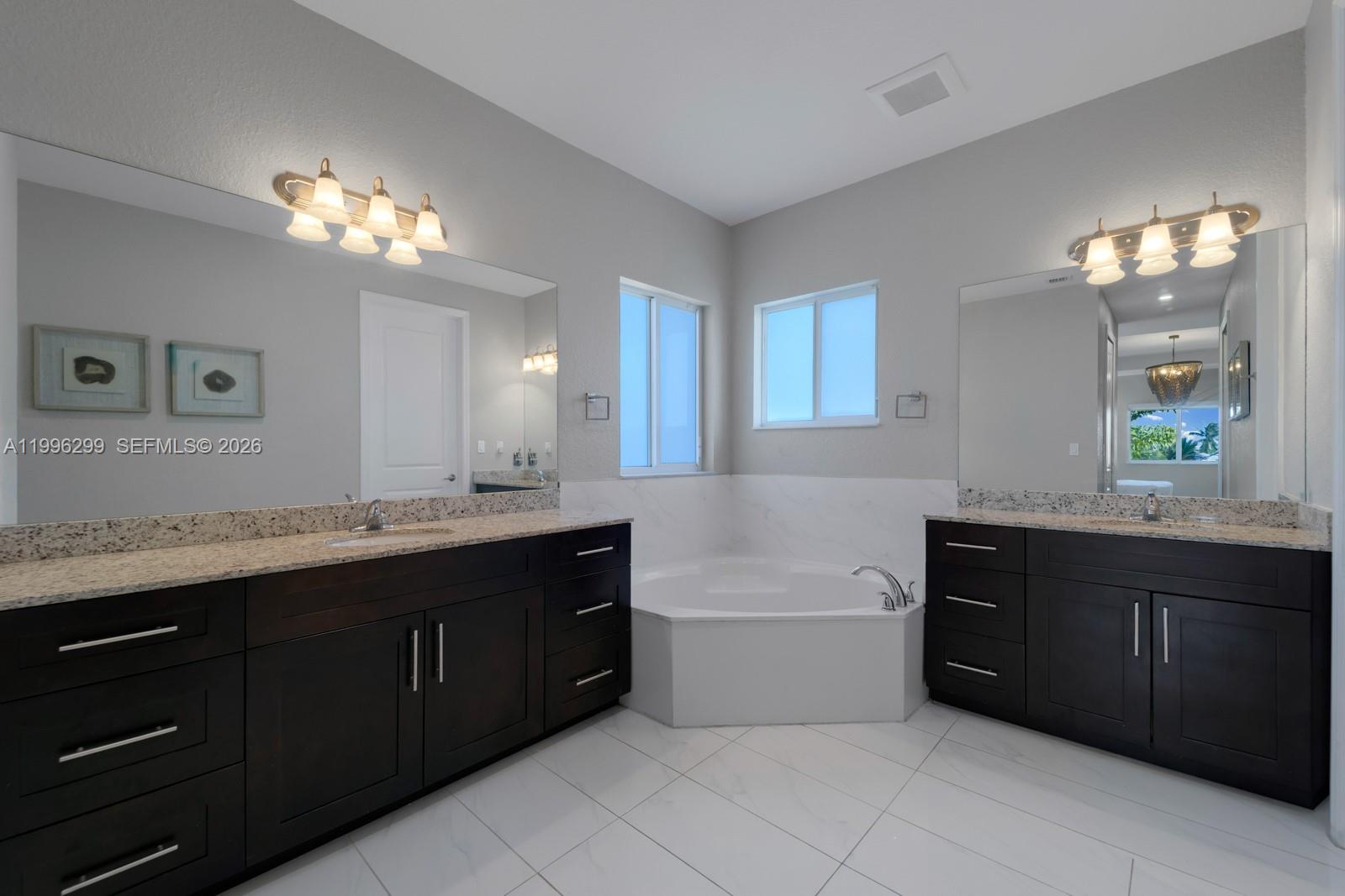 19781 Southwest 84th Court Cutler Bay, FL 33189 - Photo 27 of 53 a bathroom with a tub a double vanity sink and a mirror