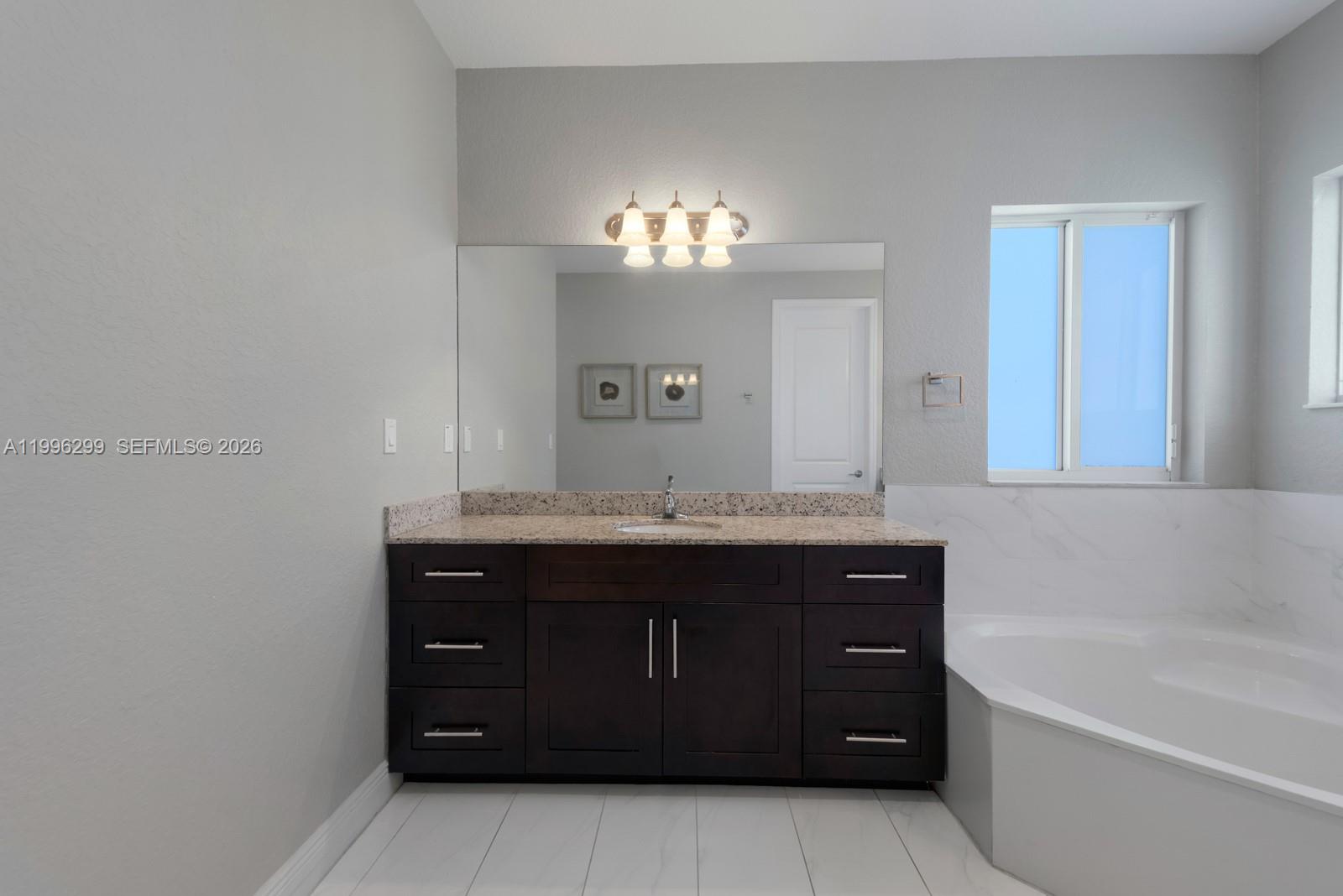 19781 Southwest 84th Court Cutler Bay, FL 33189 - Photo 28 of 53 a bathroom with a granite countertop bathtub a sink and a mirror