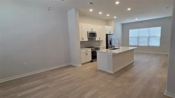 a large kitchen with stainless steel appliances granite countertop a large counter top and a wooden floor