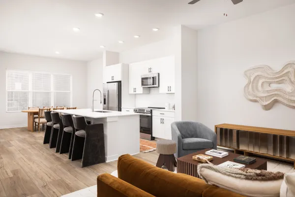 a kitchen with stainless steel appliances a table chairs refrigerator and sink