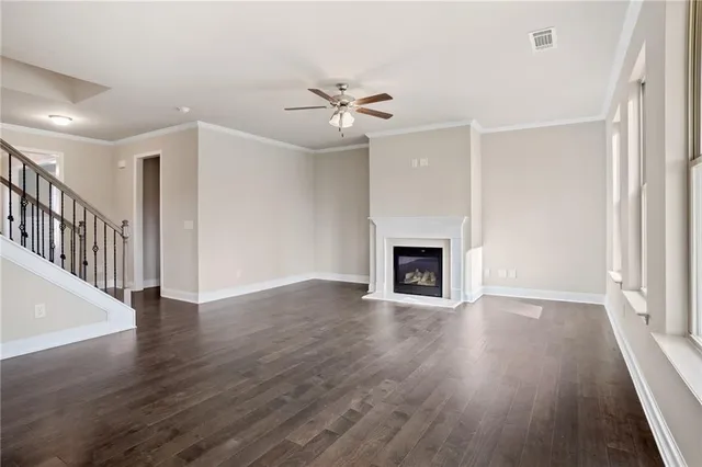 a view of an empty room with wooden floor fireplace and a window