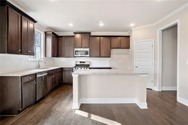 a kitchen with kitchen island granite countertop wooden cabinets a sink and white appliances
